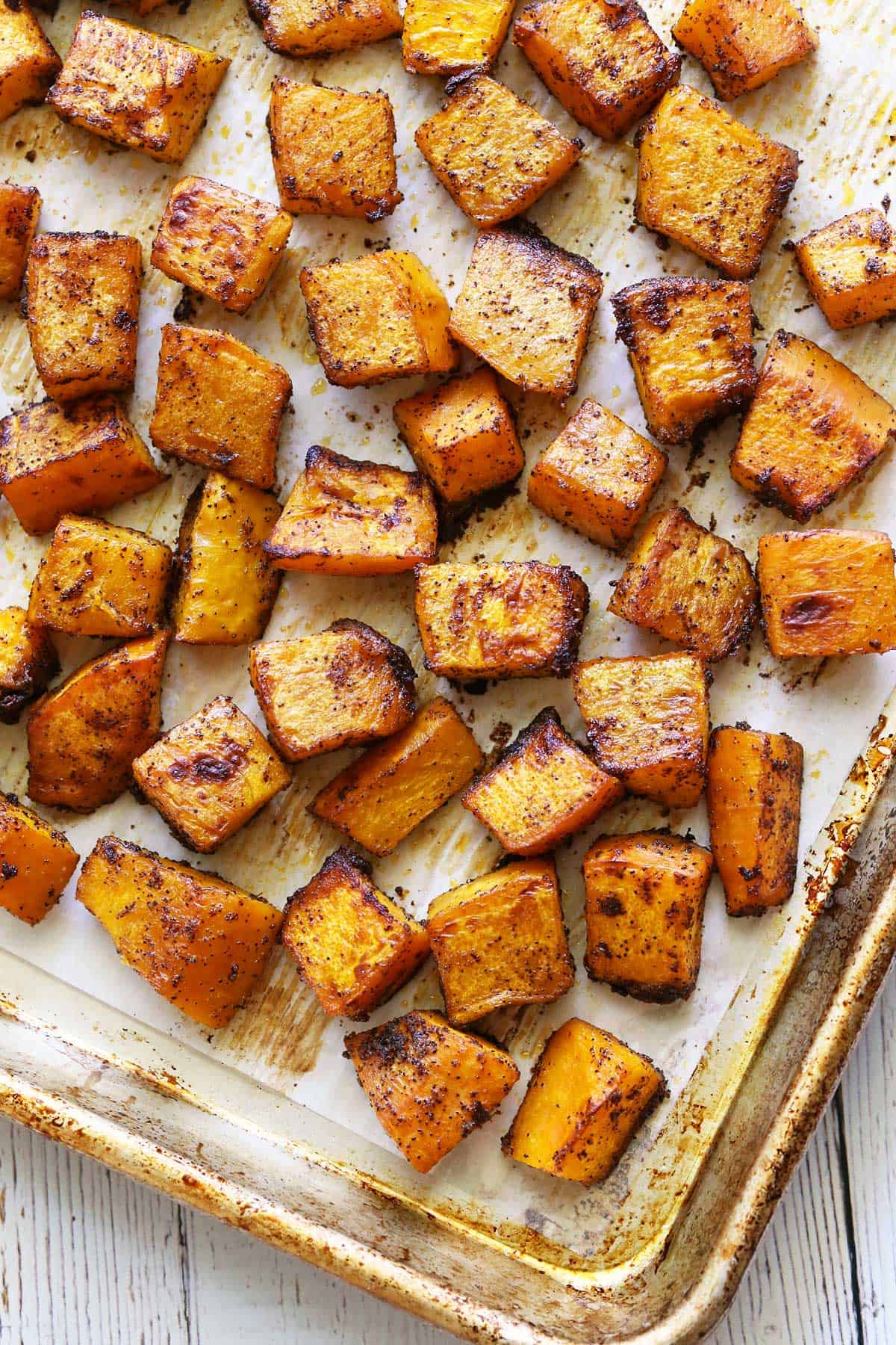 Roasted pumpkin is served on a parchment-lined baking sheet. 
