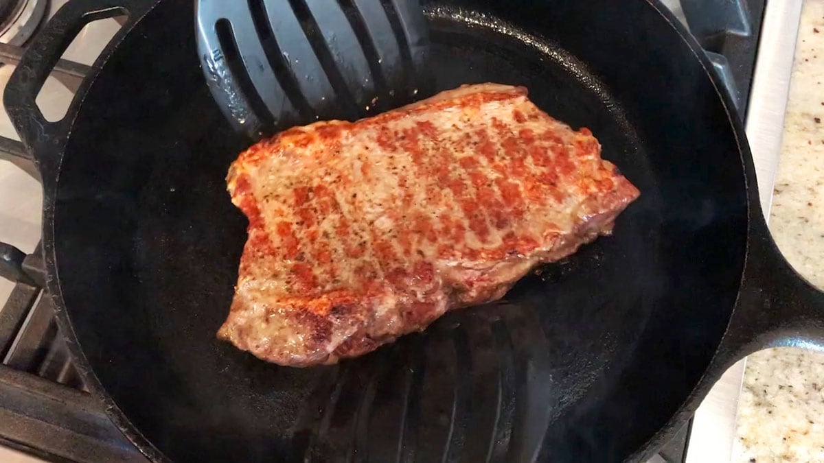 Searing the steak in a cast-iron skillet.