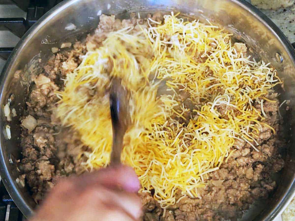 Adding cheese to the skillet.