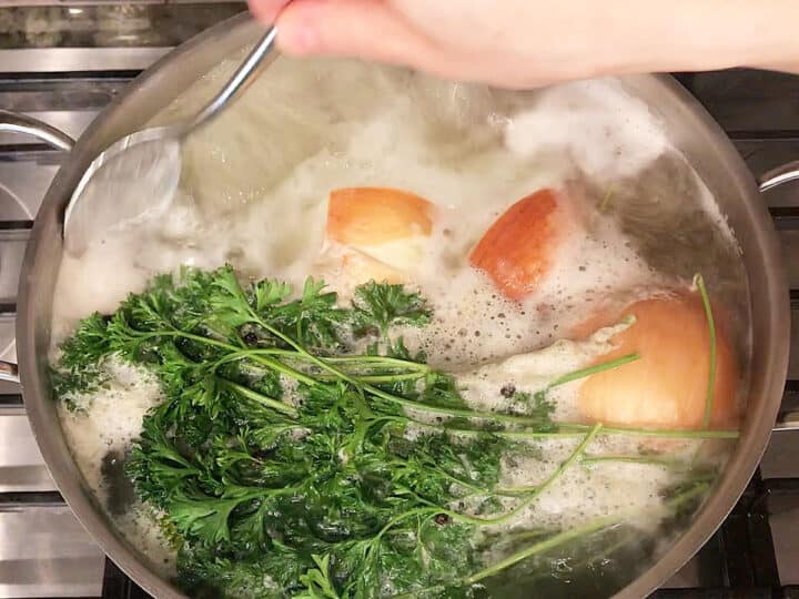 Skimming foam from the boiling broth.