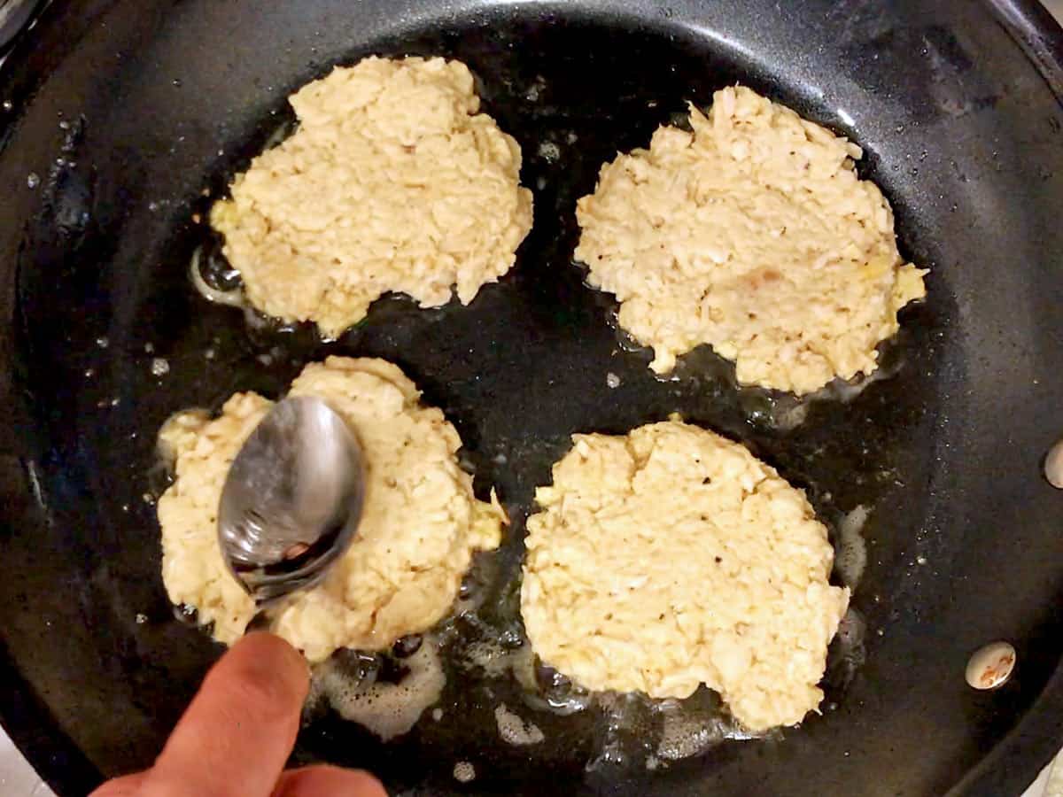 Flattening chicken patties in the skillet.