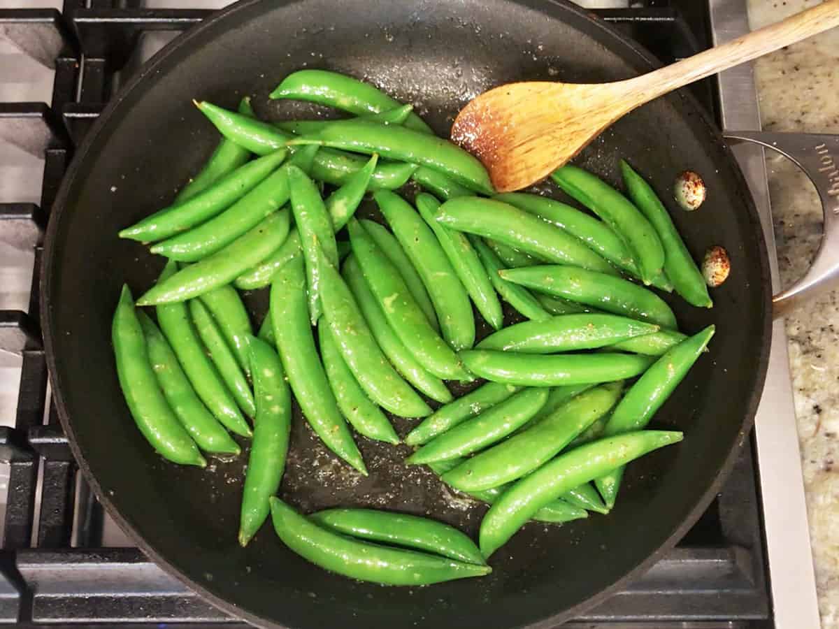 Cooking sugar snap peas in a skillet.
