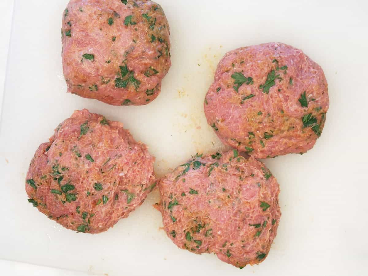 Four turkey burger patties on a cutting board. 
