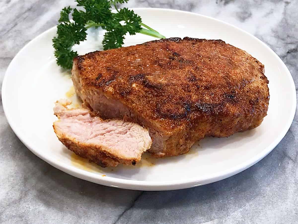 A cooked pork chop is cut to show that the inside is slightly pink. 