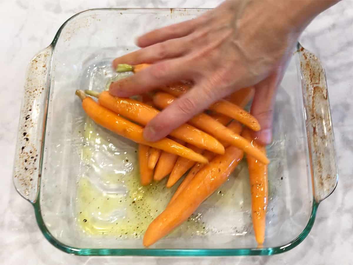 Mixing the carrots, olive oil, honey, and spices.
