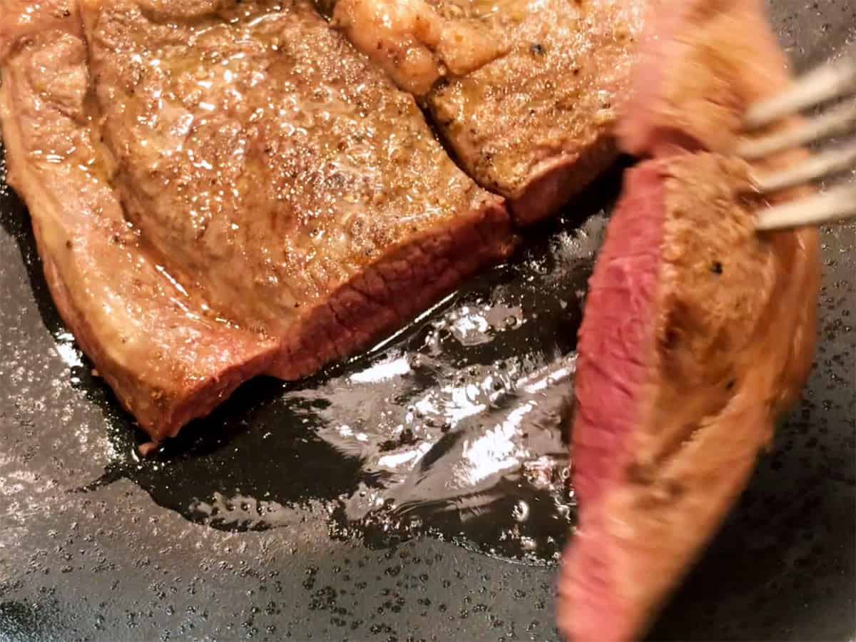 Cutting the steak to show that it's medium-rare on the inside.