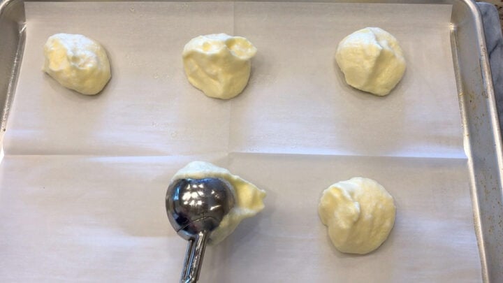 Using a scoop to transfer mounds of the mixture to the baking sheet.