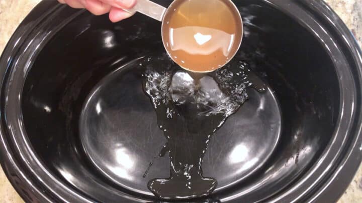Adding broth to slow cooker pan.