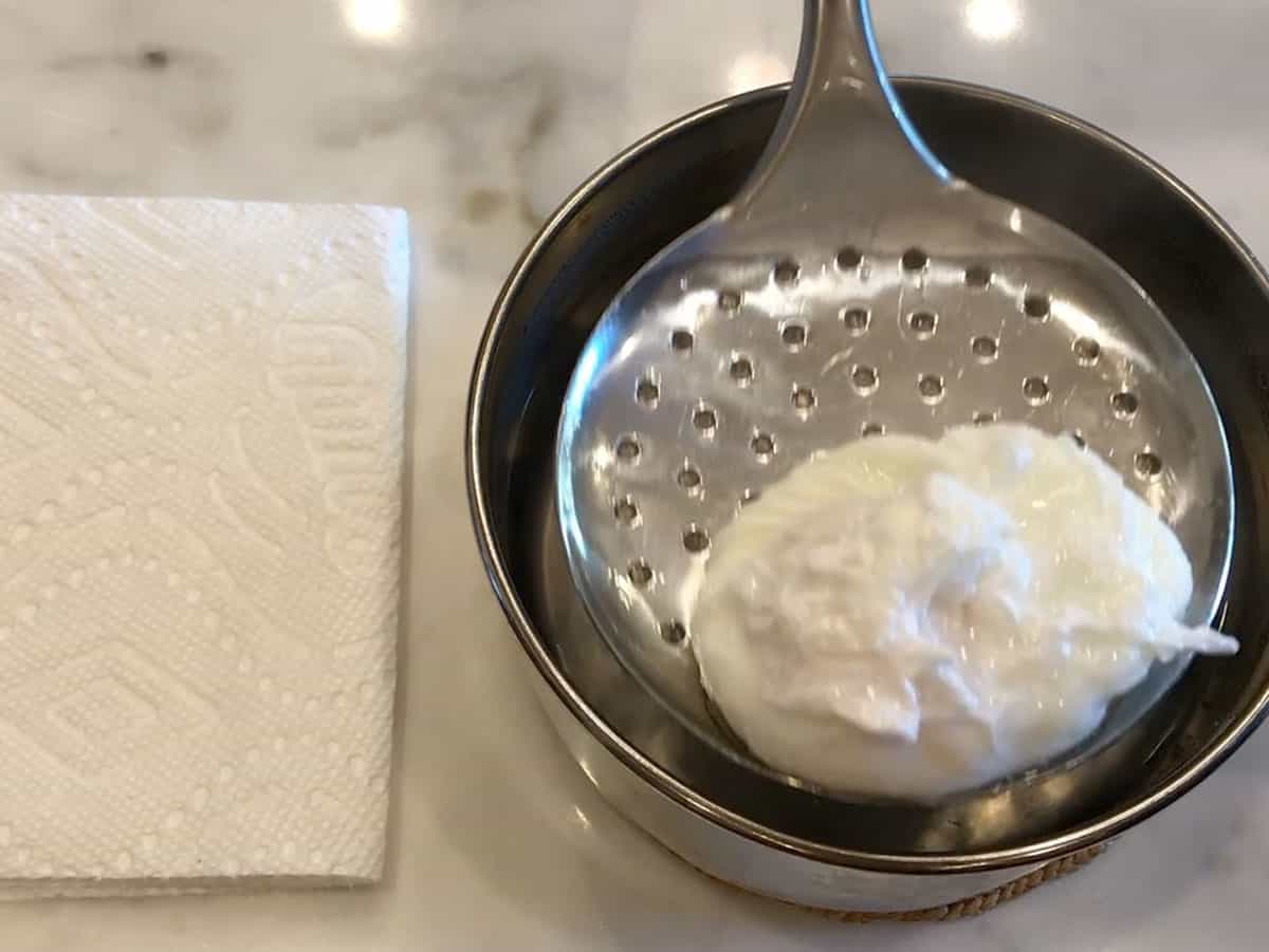 Lifting the poached egg from the water.