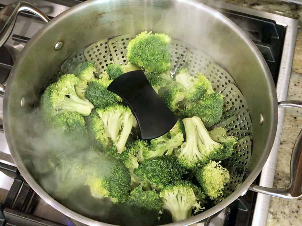 Placing the steamer basket inside a stockpot with boiling water.