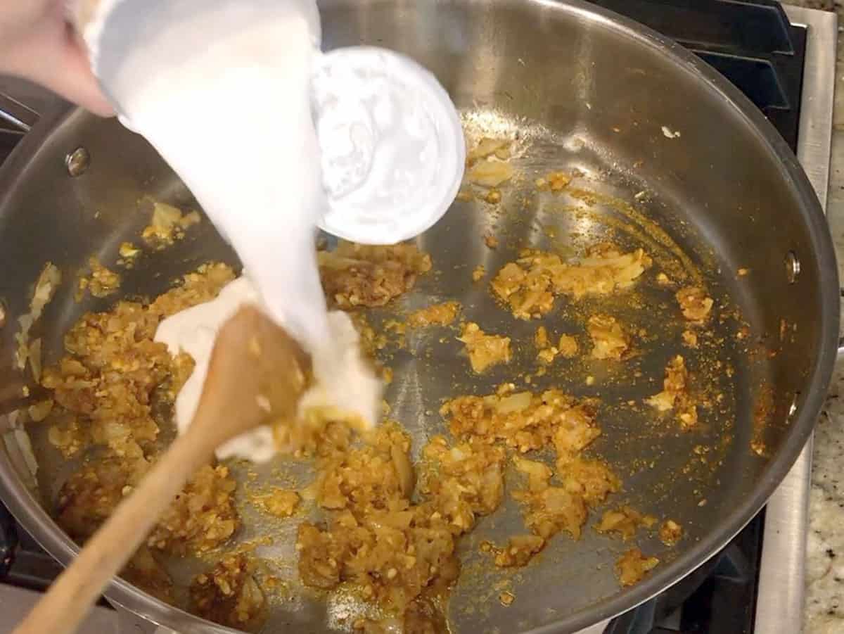 Adding coconut milk to the skillet.