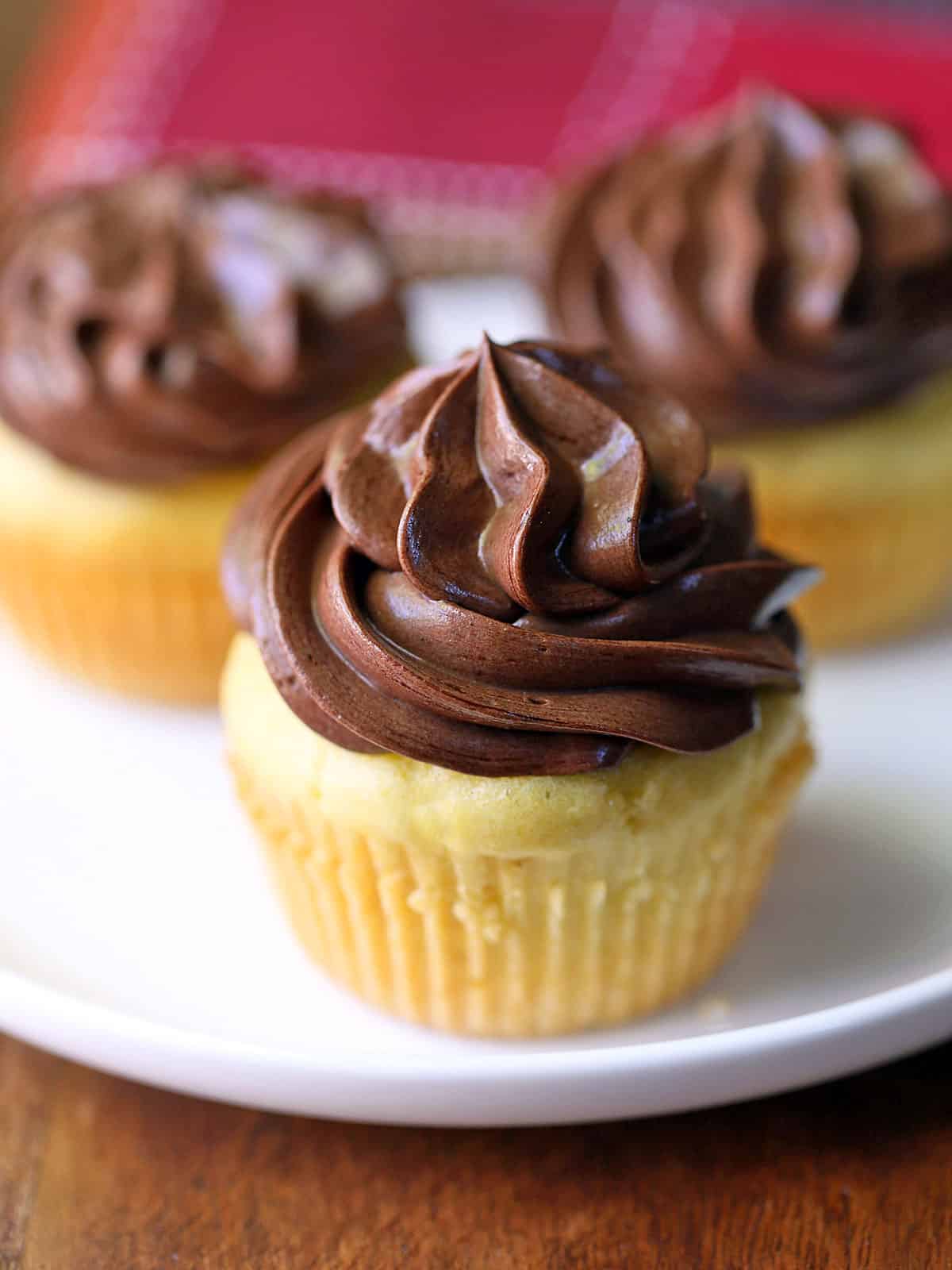 Three keto cupcakes are arranged on a white plate.