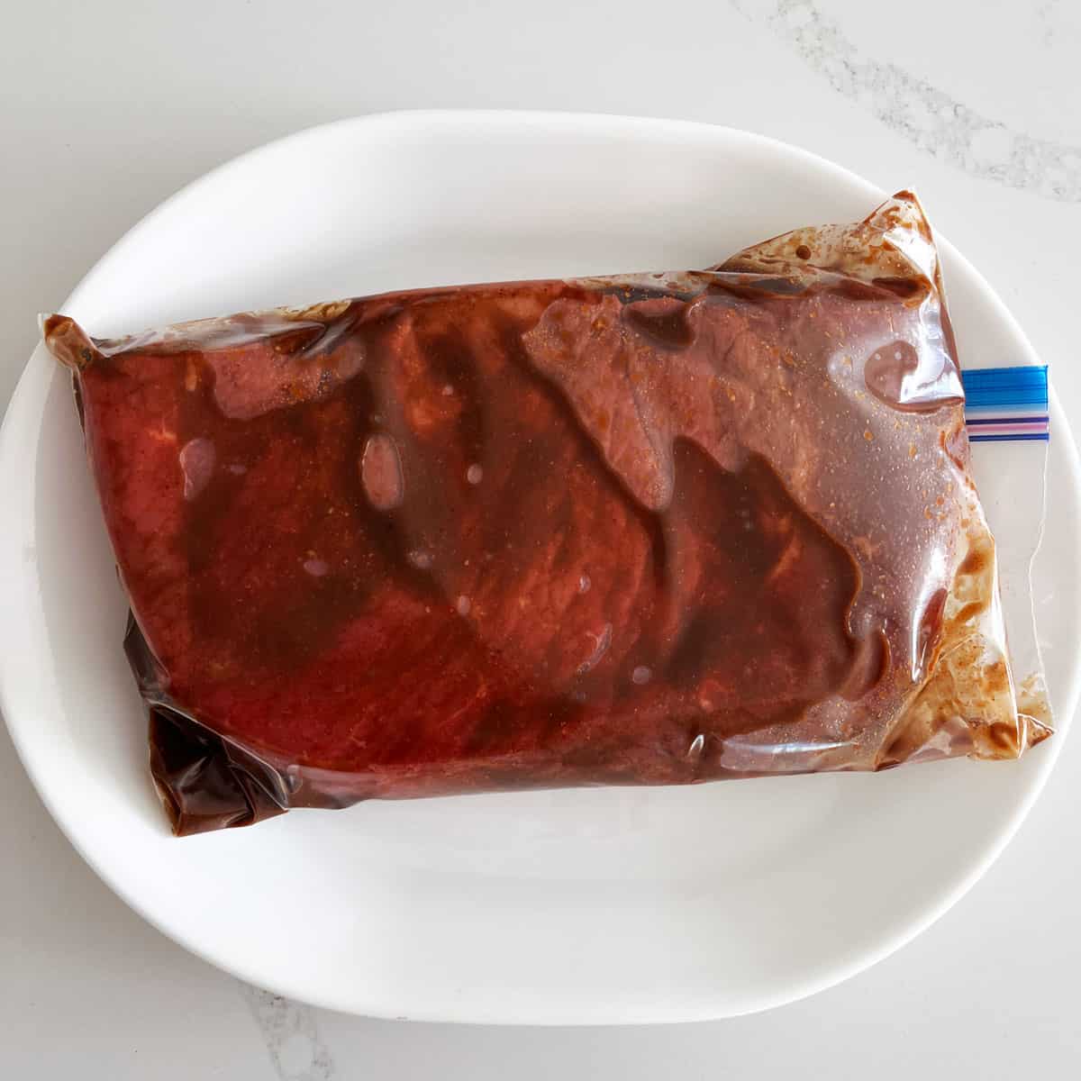 London broil steak is marinating in a Ziploc bag.