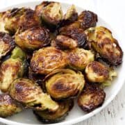 Roasted Brussels sprouts are served on a white plate.