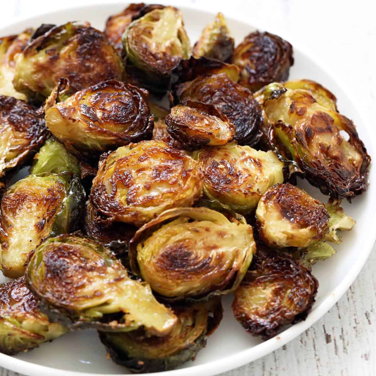 Roasted Brussels sprouts are served on a white plate.
