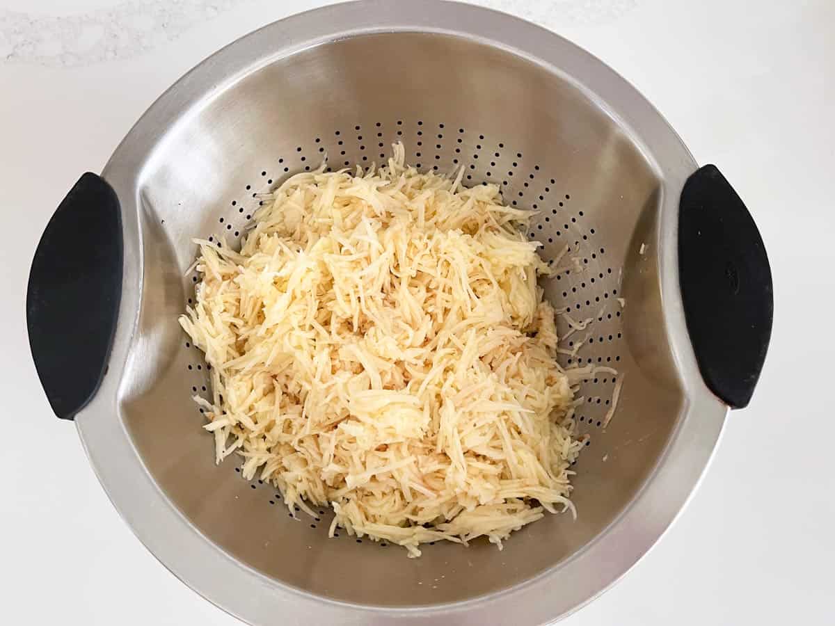 Shredded potatoes in a colander.