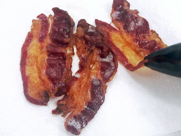 Placing the cooked bacon on paper towels.