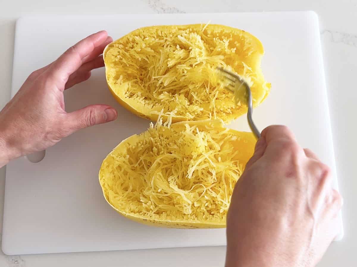Raking a fork back and forth to create spaghetti squash strands.
