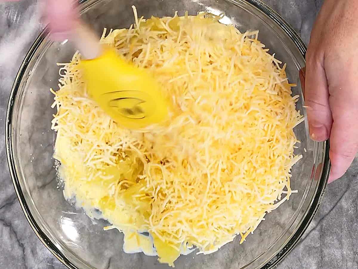 Adding shredded cheese to the bowl.