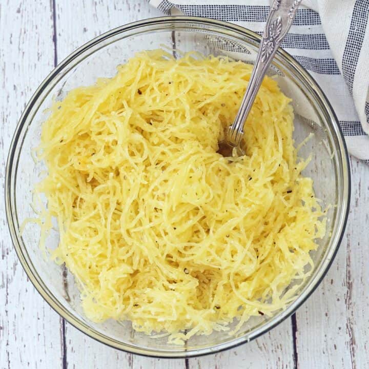 Seasoned spaghetti squash strands in a glass bowl.