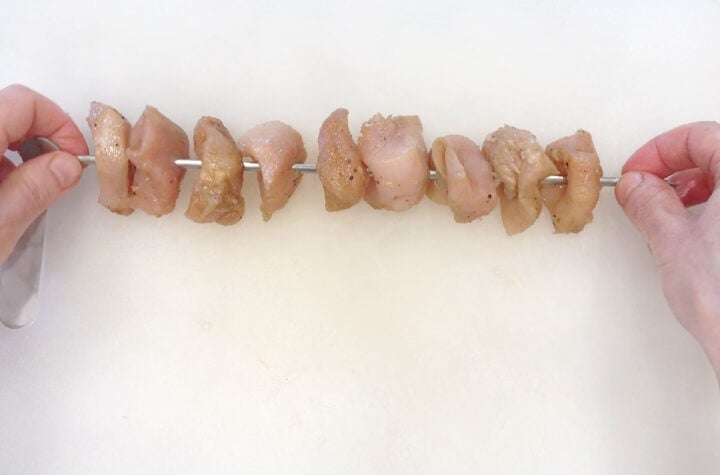 Threading the chicken pieces on skewers.