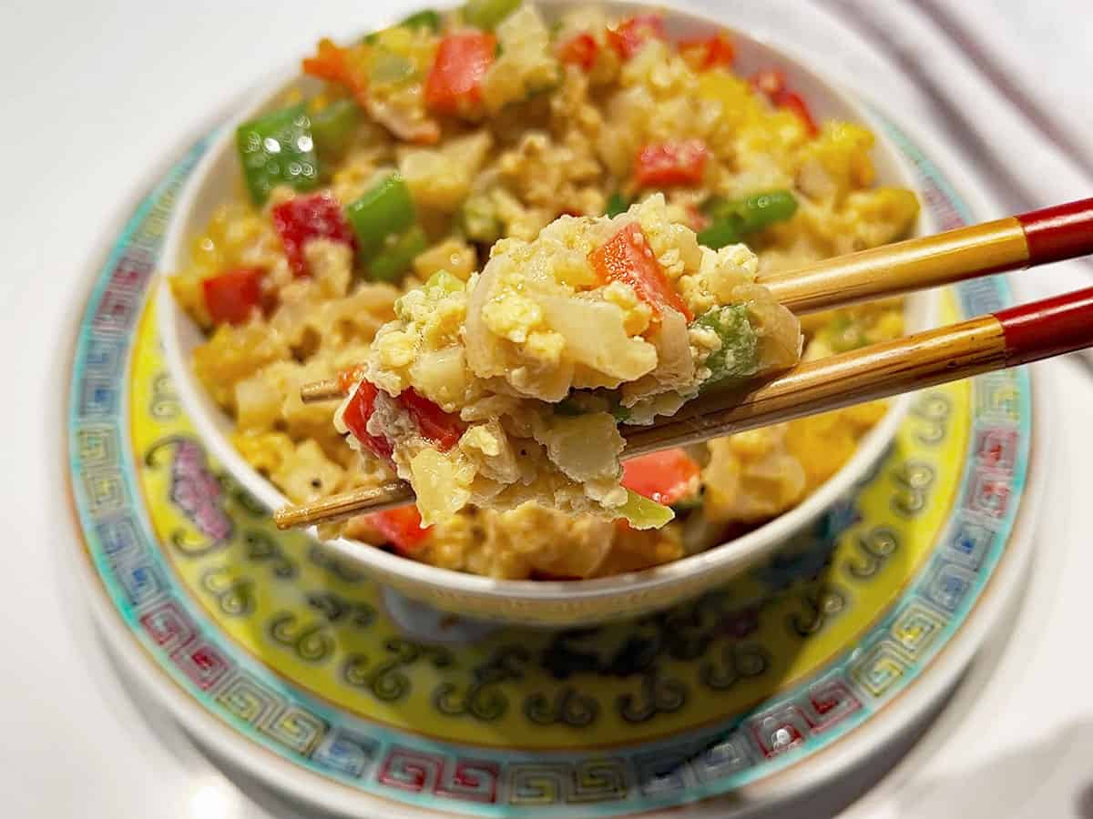 Eating cauliflower fried rice with chopsticks.