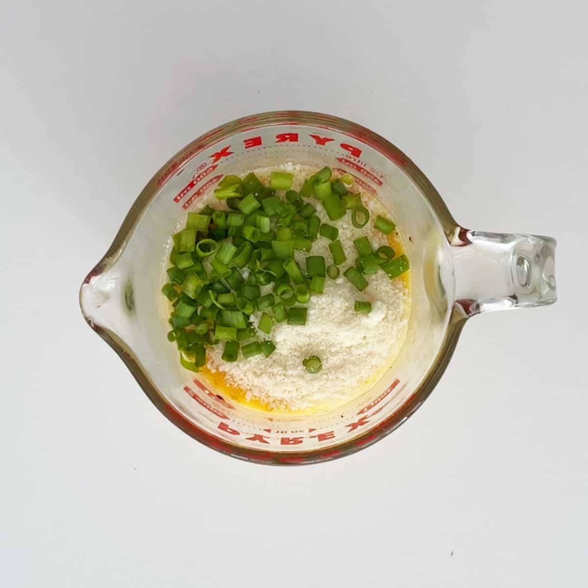 Adding parmesan and scallions to the egg mixture.