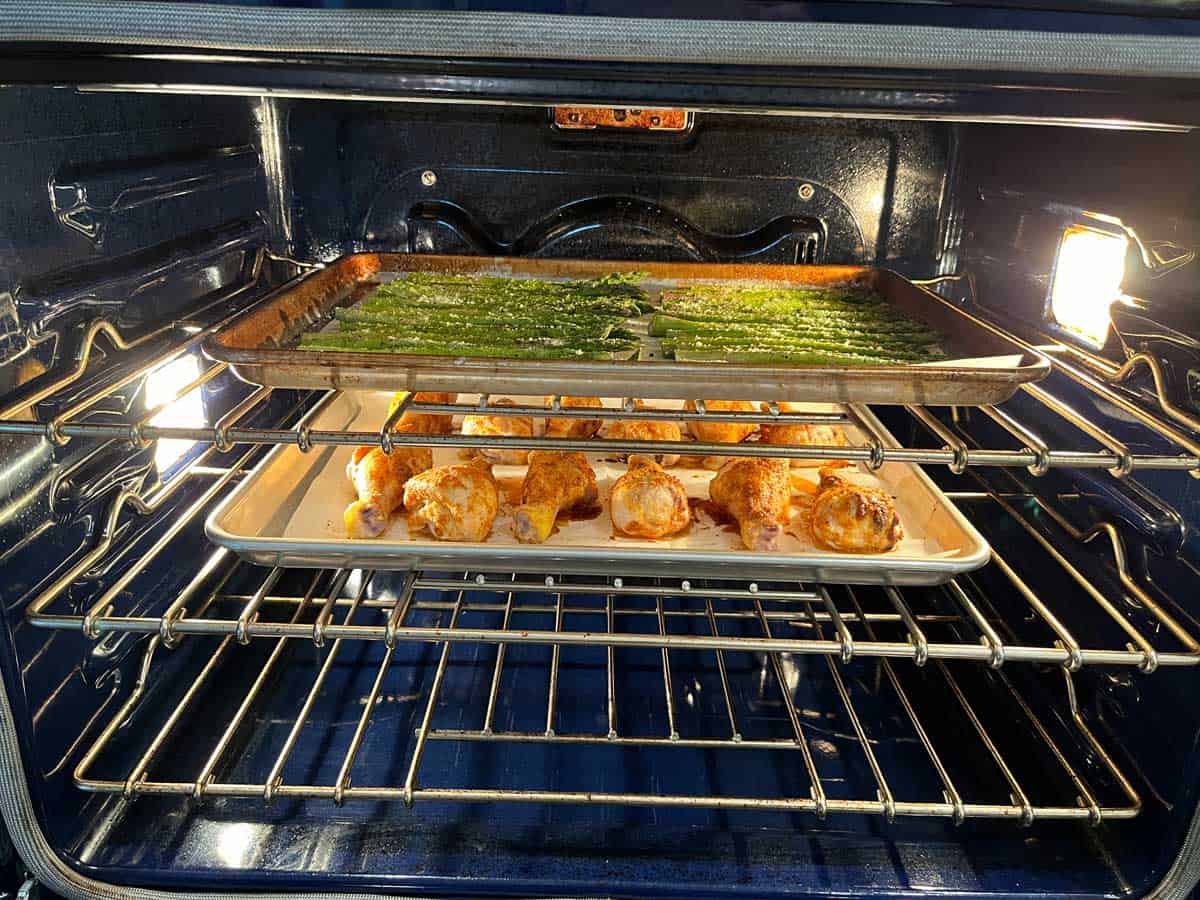 Asparagus is baked simultaneously with chicken drumsticks.
