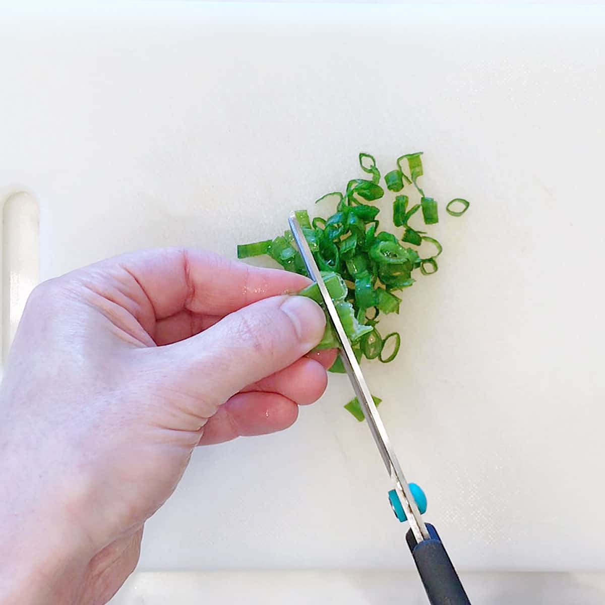 Cutting scallions with kitchen scissors.