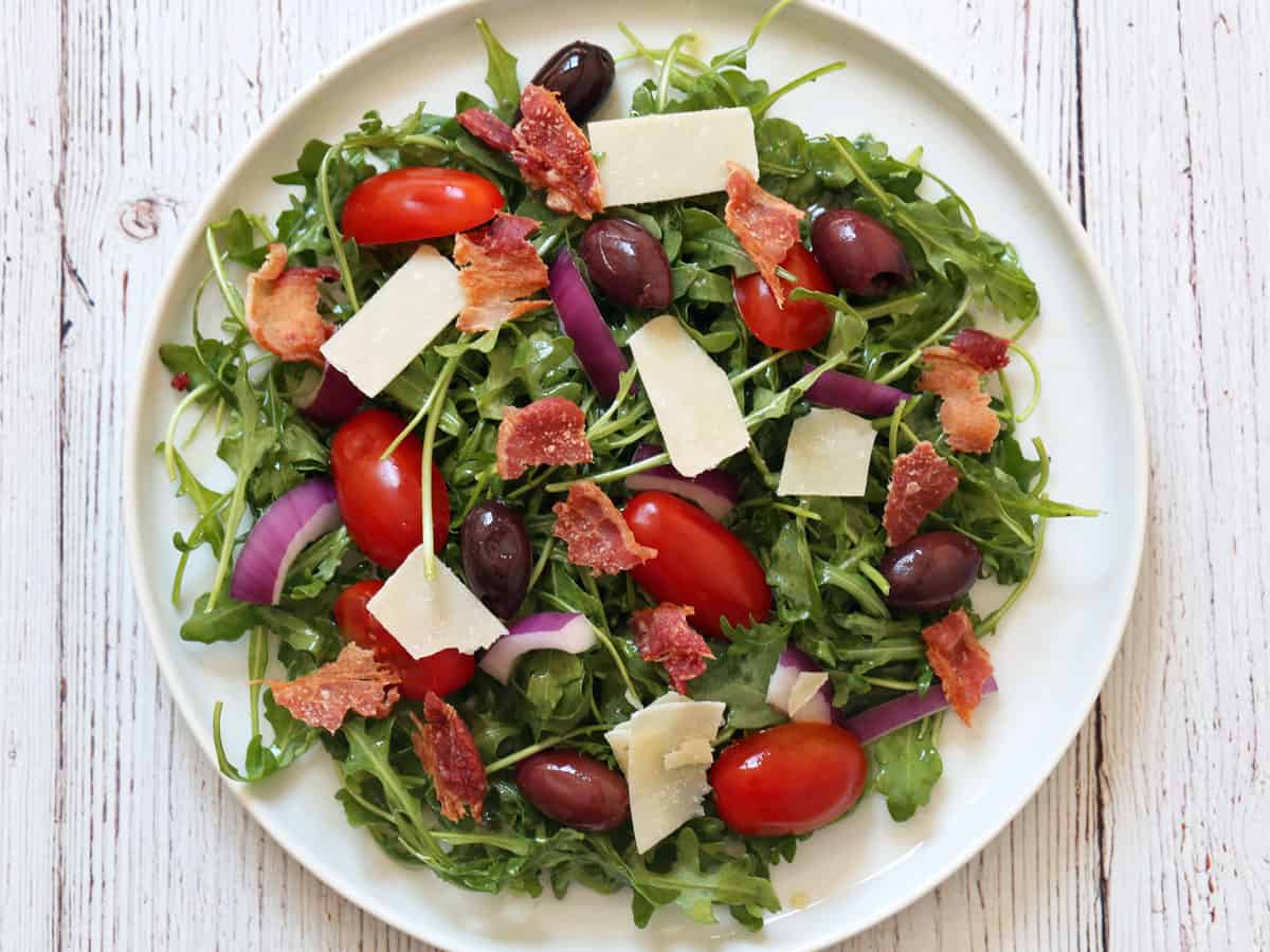 Arugula salad is topped with microwave bacon.