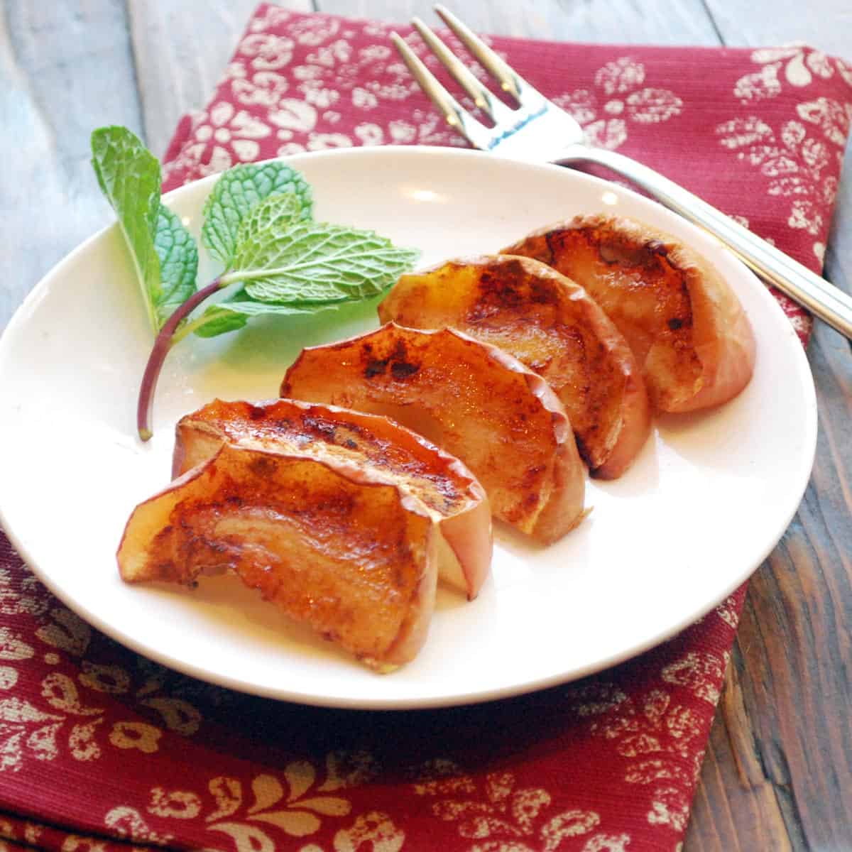Baked apple slices without butter are served on a white plate with a fork.