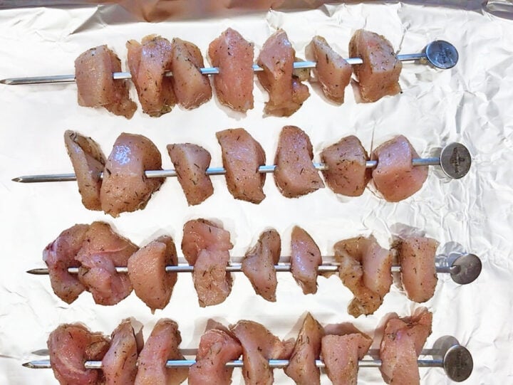 Raw chicken kabobs on a pan, ready to be baked.