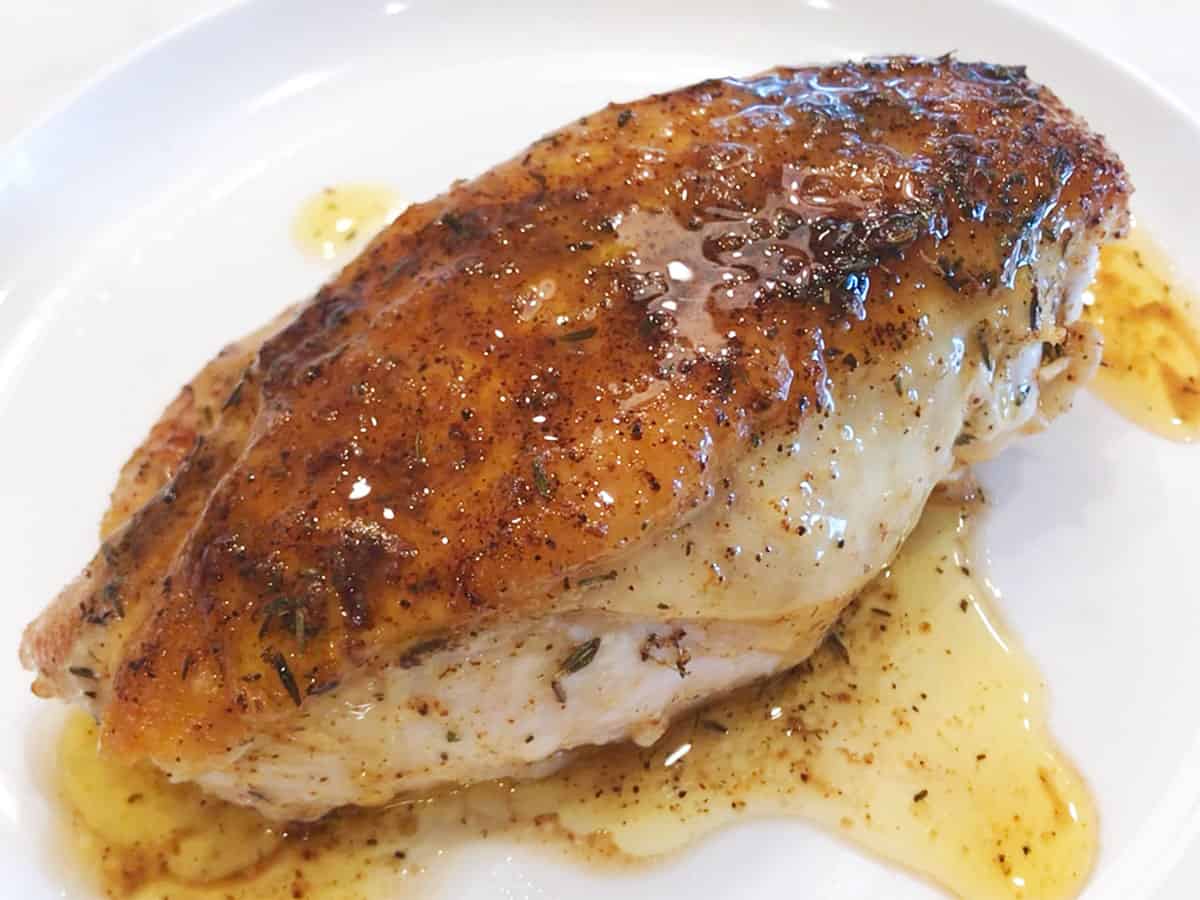 Pouring the pan juices over the chicken.