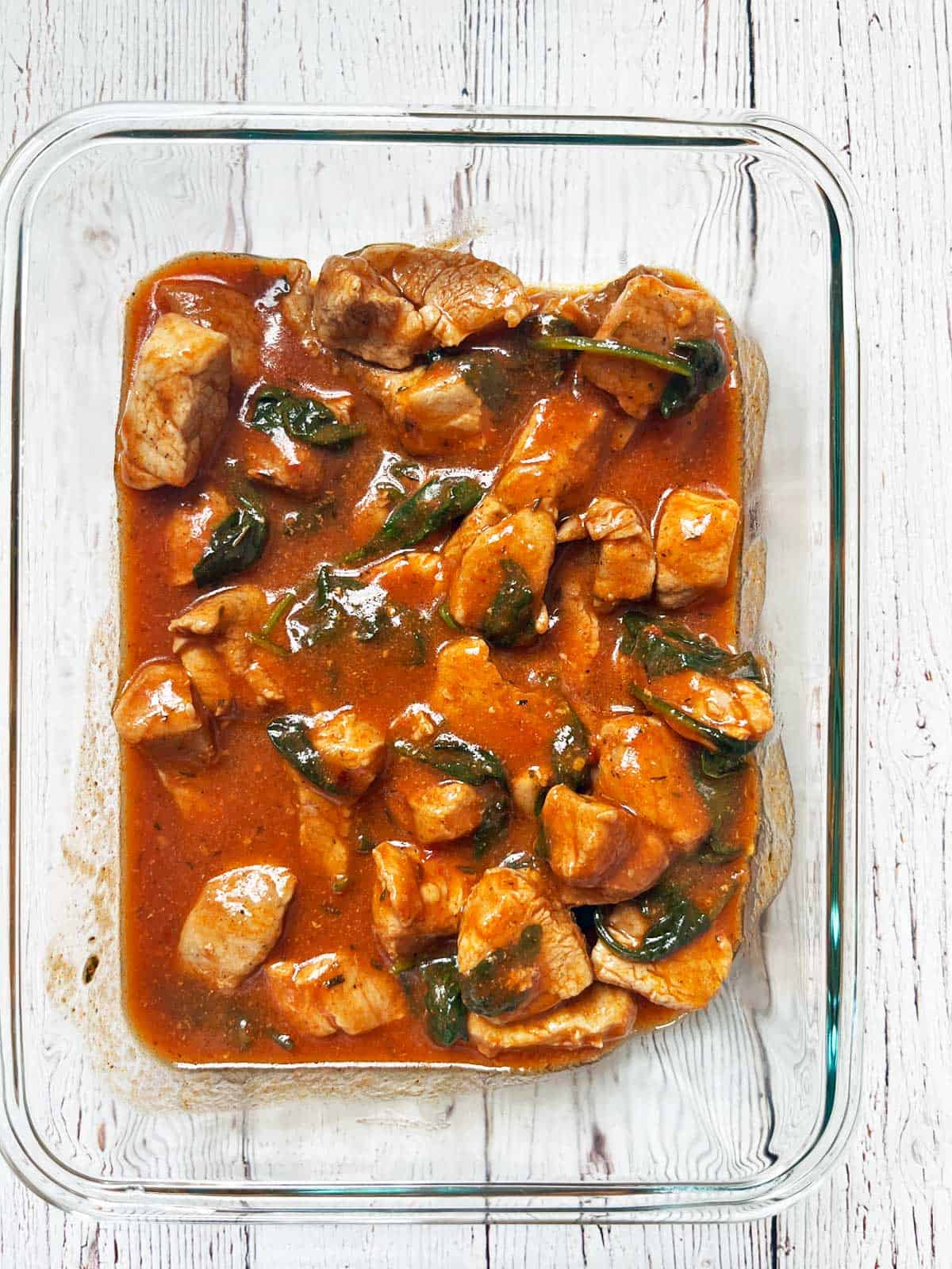 Leftover pork stew is stored in a glass food storage container.