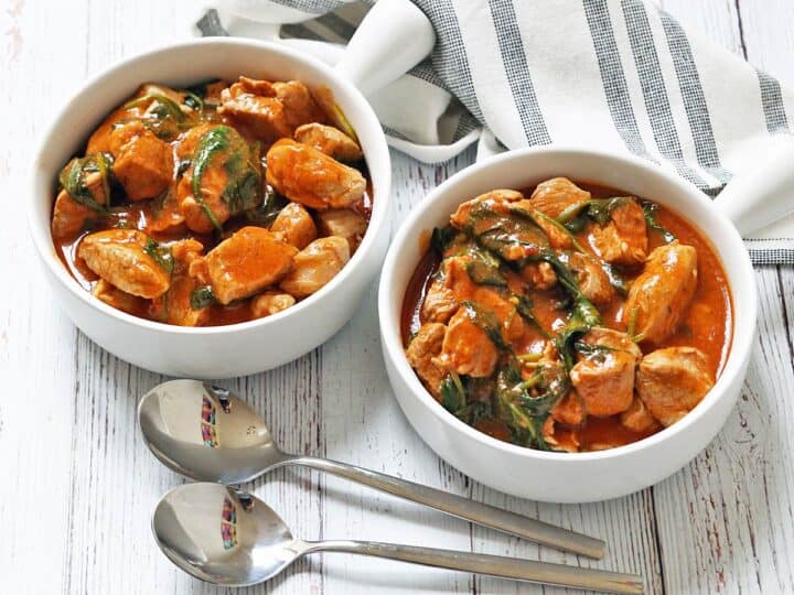 Pork stew is served in bowls with spoons.