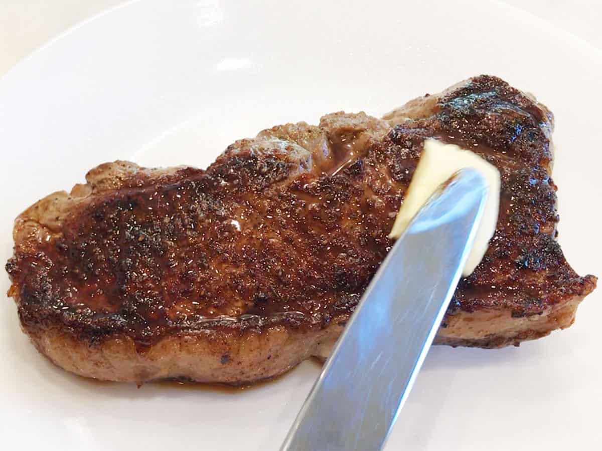 Topping the steak with butter.
