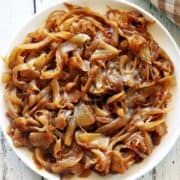Caramelized onions are served on a white plate with a napkin.