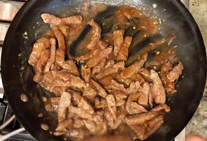 Adding the sauce to the beef in the skillet.