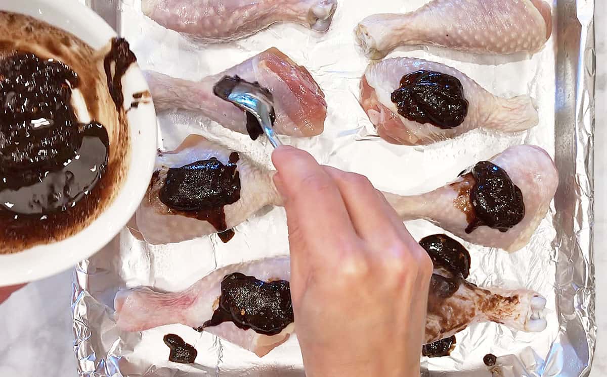 Coating the chicken in jerk seasoning.