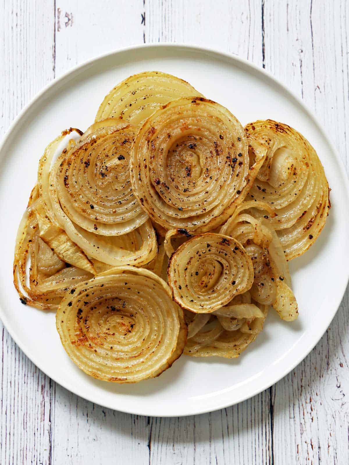 Roasted onions are served on a white plate.