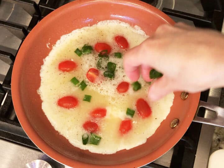 Adding veggies to the omelette.