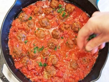 Garnishing the dish with chopped cilantro.