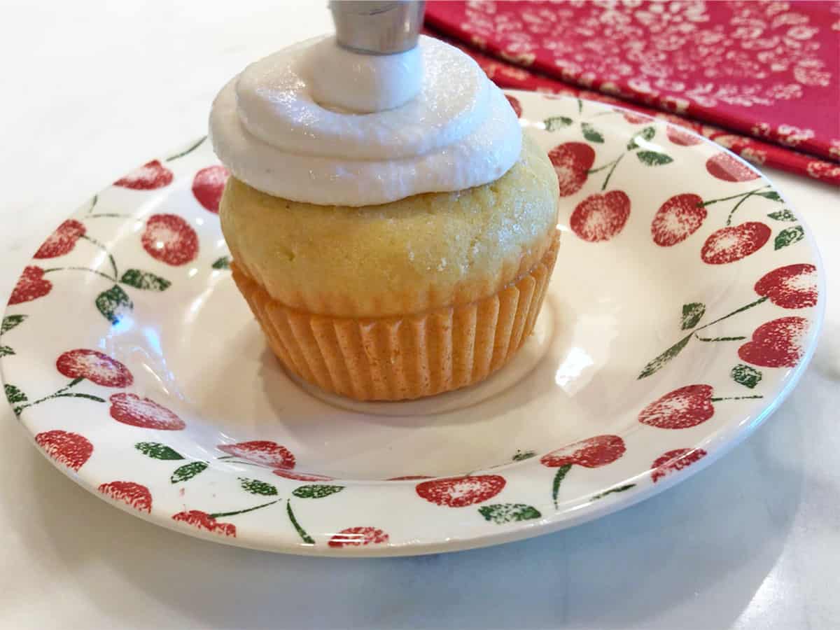 Piping the frosting on a cupcake.
