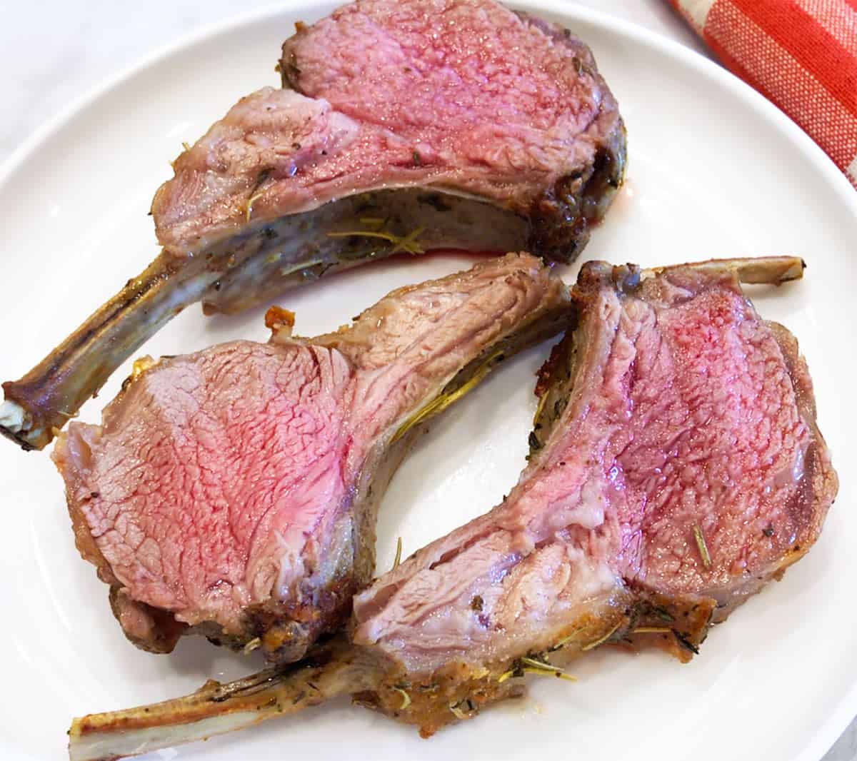 The rack of lamb was cut into individual ribs and is served on a plate.