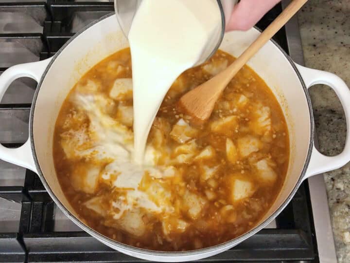 Adding heavy cream to the pot.