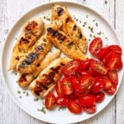 Grilled chicken tenders are served with a tomato salad.