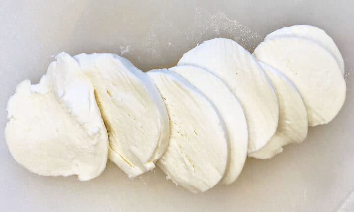 Mozzarella slices on a cutting board.