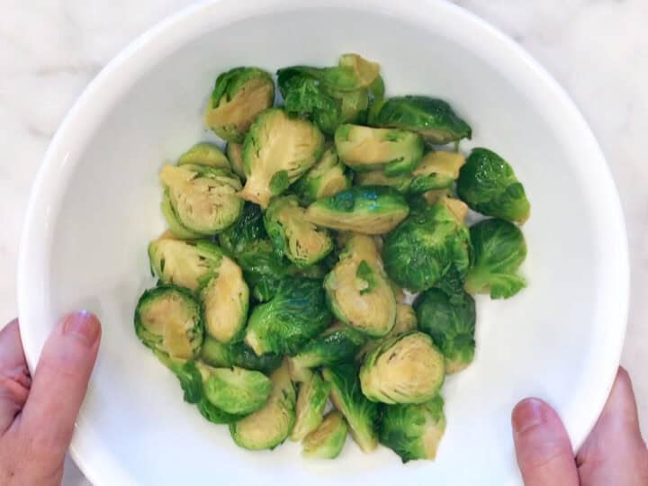Steamed Brussels sprouts in a white bowl.