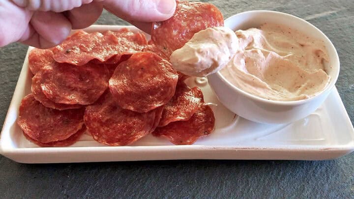 Dipping a salami chip into the dip.