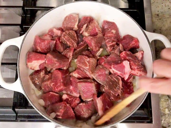Cooking onions and beef cubes in olive oil.